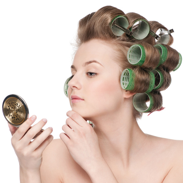 Woman in hair roller looking in mirror - Фото, изображение