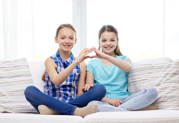 happy little girls showing heart shape hand sign - Foto, Imagen