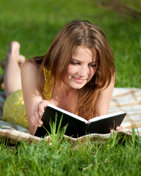 Beautiful young woman reading book outdoor - Fotó, kép