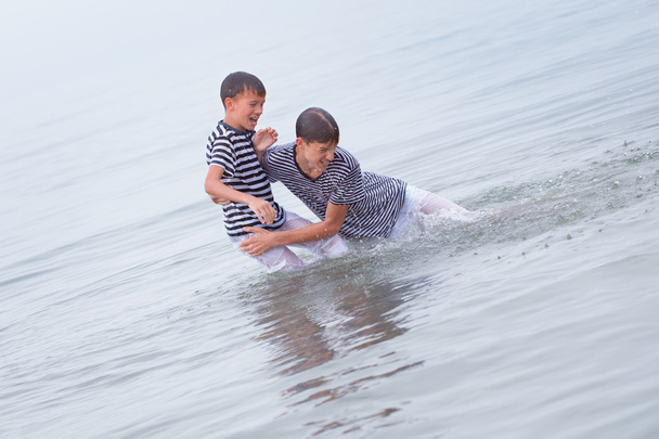 Kaksi iloinen, onnellinen, veli leikkii merellä
 - Valokuva, kuva