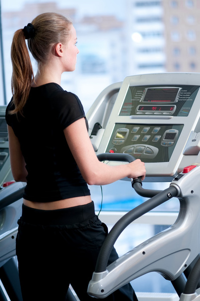 Young woman at the gym. Run on a machine - Φωτογραφία, εικόνα