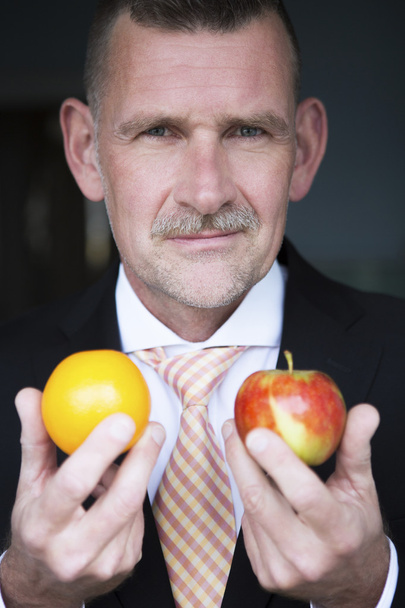 man holding orange and apple in his hands - 写真・画像
