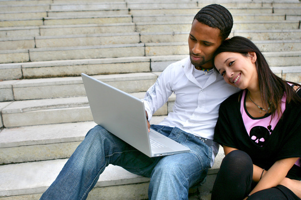 Couple sitting on some steps with a laptop - Fotoğraf, Görsel