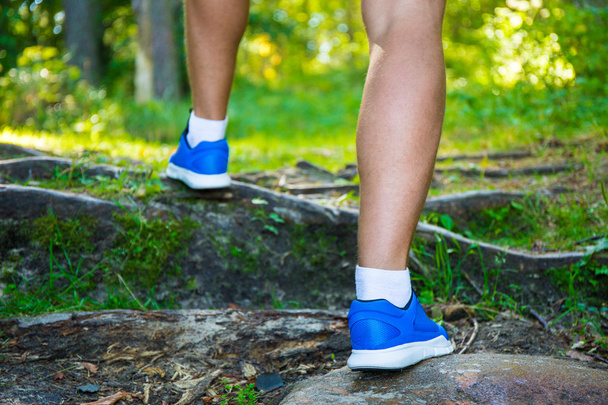 Erkek koşu ayakkabıları ormandaki bacaklarda, yakın çekim - Fotoğraf, Görsel