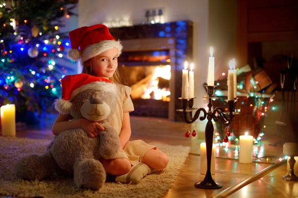 Chica sentada junto a una chimenea en Nochebuena
 - Foto, imagen