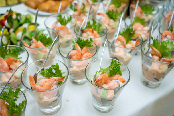 Shrimp or Prawn Cocktail snacks in shot glasses on table. Healthy Shrimp Salad with mixed greens and tomatoes. - Photo, Image