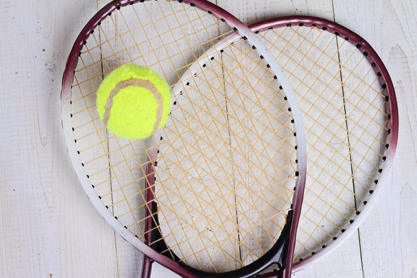 Heart shape made from tennis rackets. Close up on tennis racket and ball. Sport equipment background, wallpaper - Photo, Image