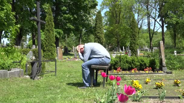 Stressed man shrink near mother lover grave in cemetery. 4K - Footage, Video