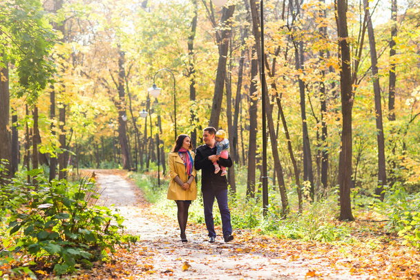 Familia joven para dar un paseo en el parque de otoño con el bebé
 - Foto, Imagen