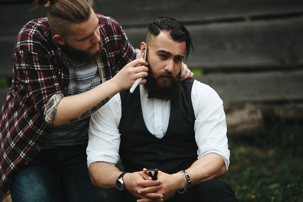 barbero afeita a un hombre barbudo
 - Foto, Imagen