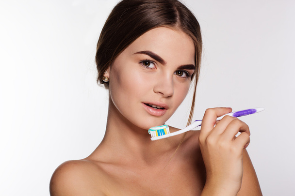 Chica está sosteniendo cepillo con pasta de dientes aislado en blanco
 - Foto, imagen