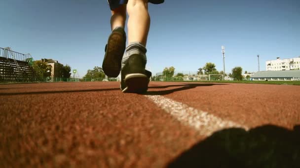 Nastolatek zawodnik chłopiec biegacz na bieżni stadionu sun słoneczny dzień zdrowego stylu życia - Materiał filmowy, wideo