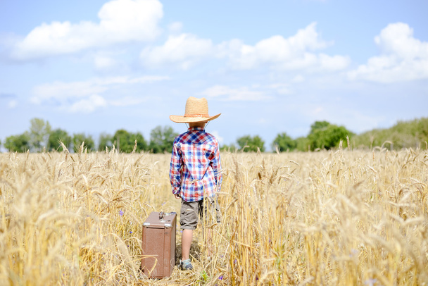 Boy in straw cowboy hat standing in golden wheat field - Valokuva, kuva