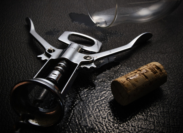 Corkscrew com cortiça de vinho e vidro na superfície molhada preta
 - Foto, Imagem