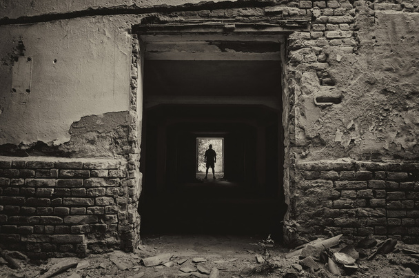 Silhouet van de man die aan het einde van donkere gang van verlaten ingebouwde - Foto, afbeelding
