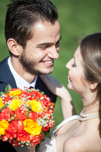 Happy just married bride and groom on green grass background - Zdjęcie, obraz