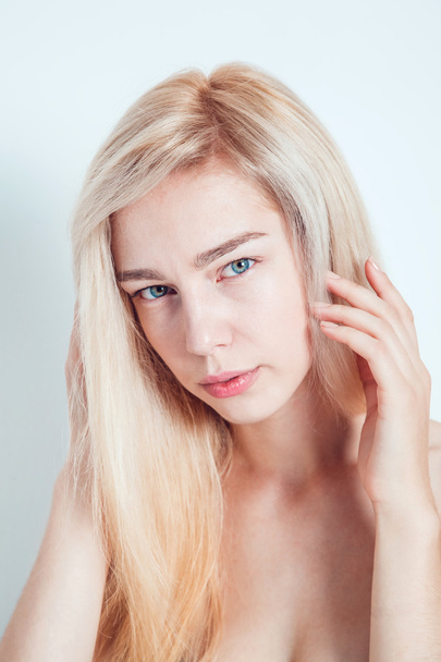 Beautiful blond with green eyes on a light background. She looks into the camera. Fashionable hair color. A good manicure. - Foto, afbeelding