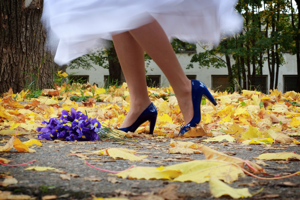 Stock Photo: bride is dancing on the yellow leafs wearing her blue heels - Photo, Image