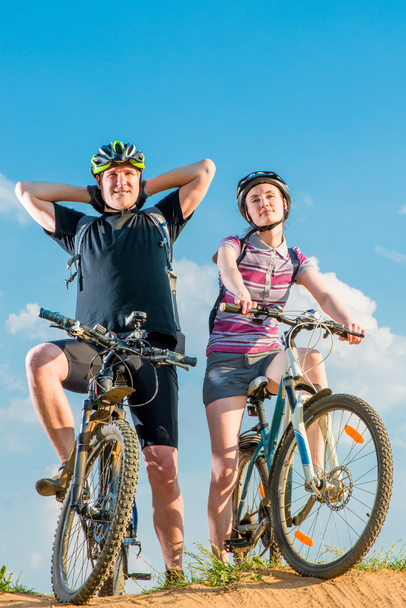 um par de ciclistas em capacetes em bicicletas posando
 - Foto, Imagem