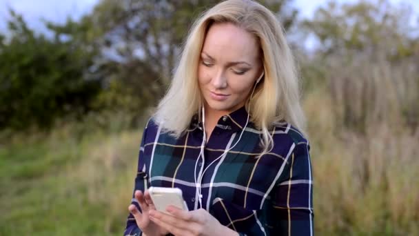 Mujer joven escuchando música en su smartphone
 - Metraje, vídeo