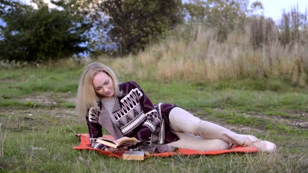 Mladá žena na lůžku. čtení knihy a usmívá se na kameru - Záběry, video
