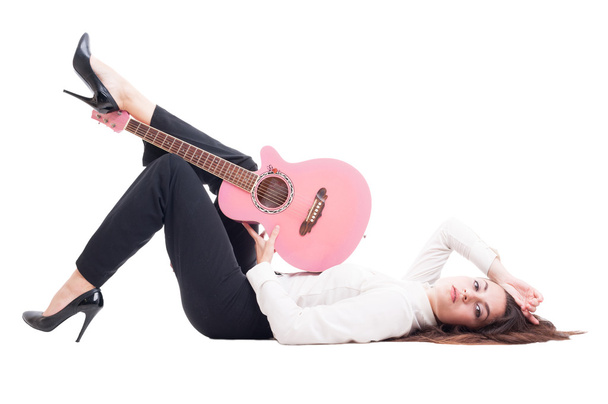 Красива молода жінка-гітаристка лежить на білій підлозі
 - Фото, зображення