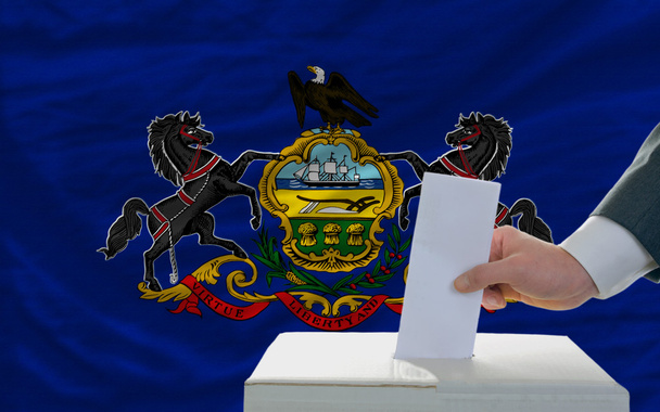Mies äänestää Yhdysvaltain lipun alla pidettävistä vaaleista
 - Valokuva, kuva