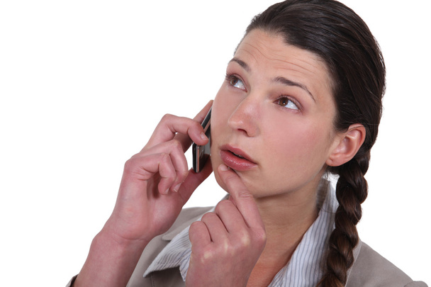 Doubtful woman talking on her mobile phone - Zdjęcie, obraz