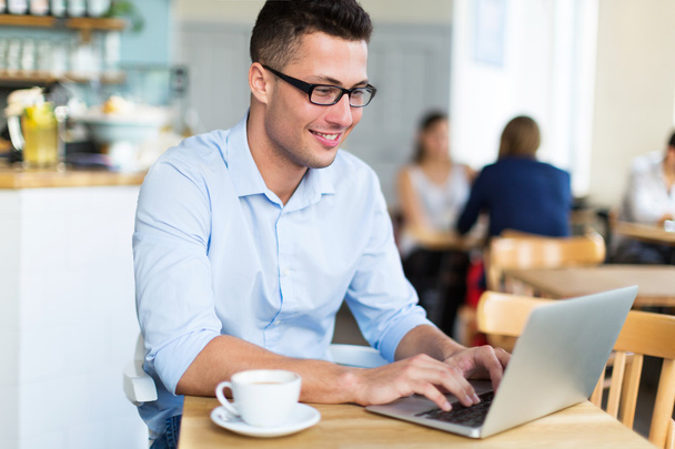 Junger Mann benutzt Laptop im Café - Foto, Bild