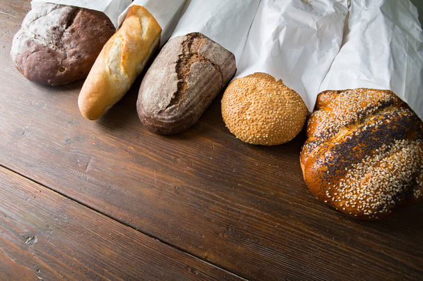 Fresh baked bread at wooden table - Fotoğraf, Görsel
