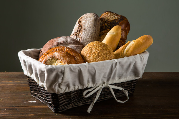 Photo of the assorted bread in wooden basket - Фото, изображение