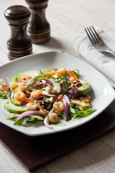 Salad with avocado and prawns on the ceramic plate with salt and pepper shaker - Zdjęcie, obraz
