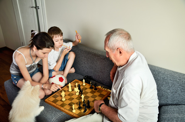 grandchildren with grandpa playing chess - Foto, afbeelding