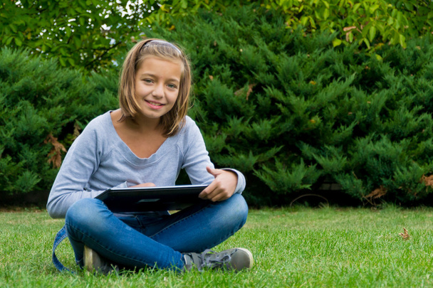 Child with laptop sitting in grass - Photo, Image