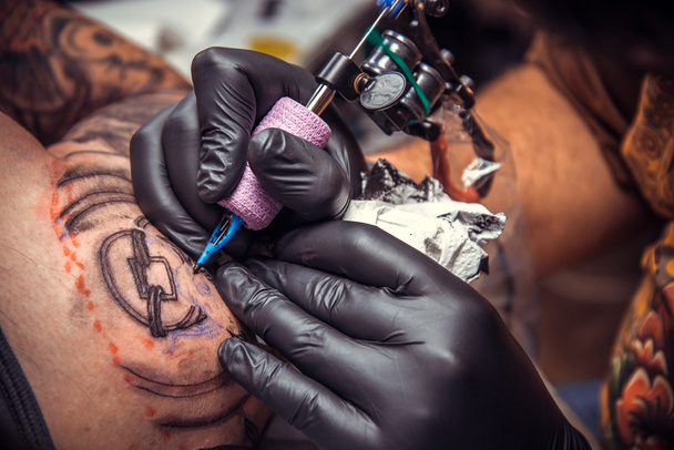Professional tattooist makes cool tattoo in tattoo parlor - Photo, Image