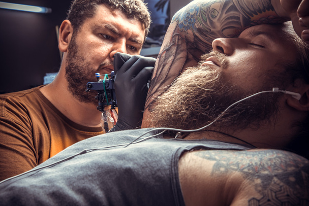 Maestro del tatuaje haciendo tatuaje en salón de tatuaje
 - Foto, Imagen
