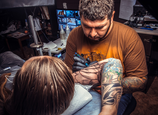 Tattoo specialist showing process of making a tattoo in studio - Photo, Image