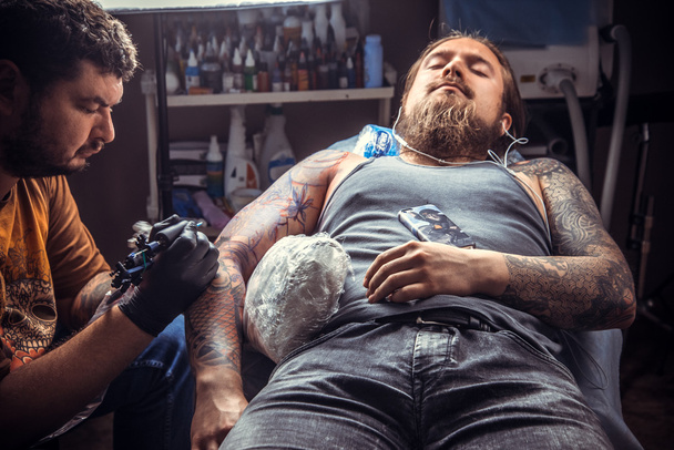 Especialista en tatuajes hace fotos de tatuaje en estudio de tatuaje
 - Foto, Imagen