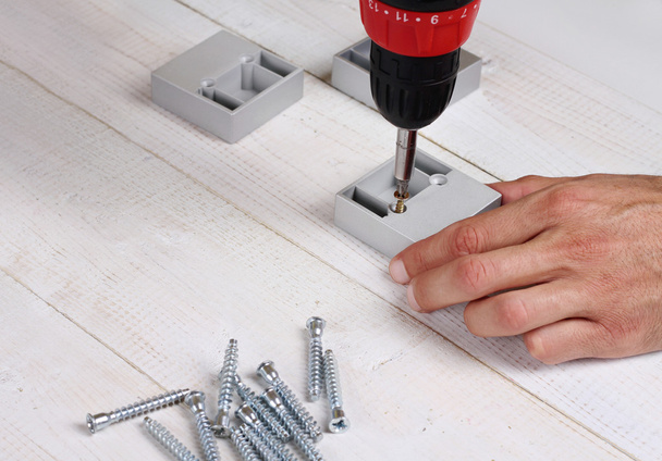 Nahaufnahme männlicher Hände mit einem elektrischen Schraubenzieher, der Möbel fixiert. Werkzeuge, Haushaltsgeräte - Foto, Bild