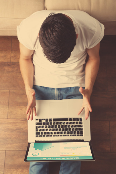 Young man sitting on floor with laptop in room - Foto, Imagem