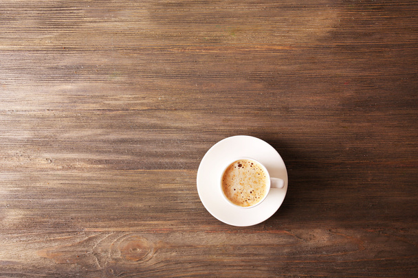Cup of coffee with foam on wooden table, top view - Foto, imagen