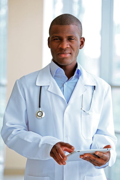 Handsome African American doctor holding digital tablet in hospital - Foto, Imagen