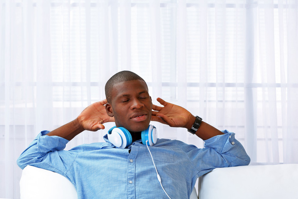 Handsome African American man with headphones lying on sofa close up - Fotoğraf, Görsel