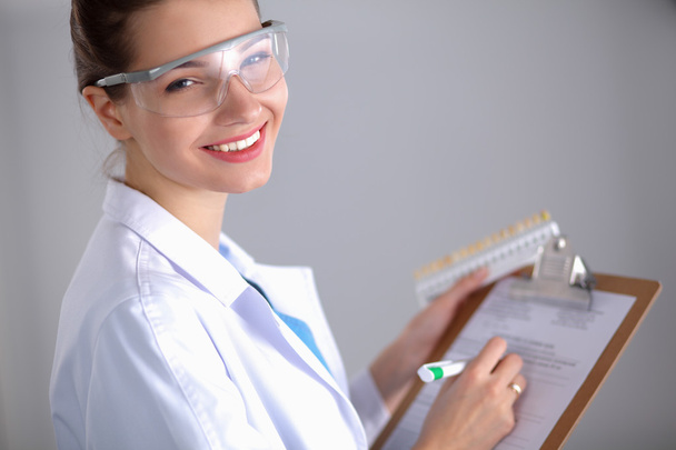 Smiling female doctor with a folder in uniform standing at hospital - Foto, imagen