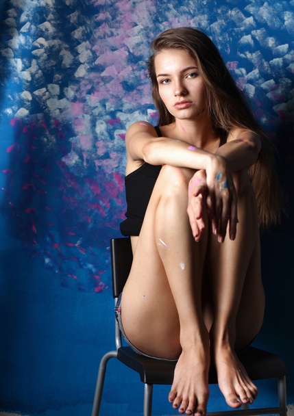 Young woman sitting near painting wall - Foto, imagen