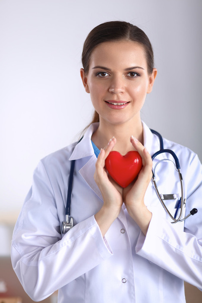 Young woman doctor holding a red heart - Foto, Bild