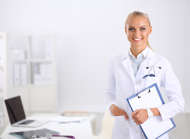 Усміхнена жінка-лікар з папкою в уніформі, стоячи в лікарні
 - Фото, зображення