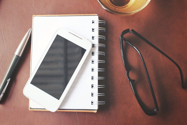 Bloco de notas em branco e telefone inteligente com chá quente na mesa de escritório
 - Foto, Imagem