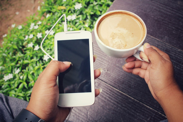 Kobieta, smartphone rezygnować słuchawki i kawę w ogrodzie - Zdjęcie, obraz