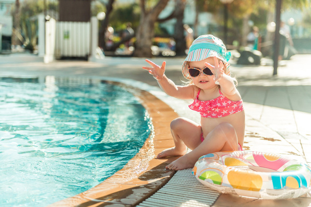 Mała dziewczynka siedzi przy basenie - Zdjęcie, obraz